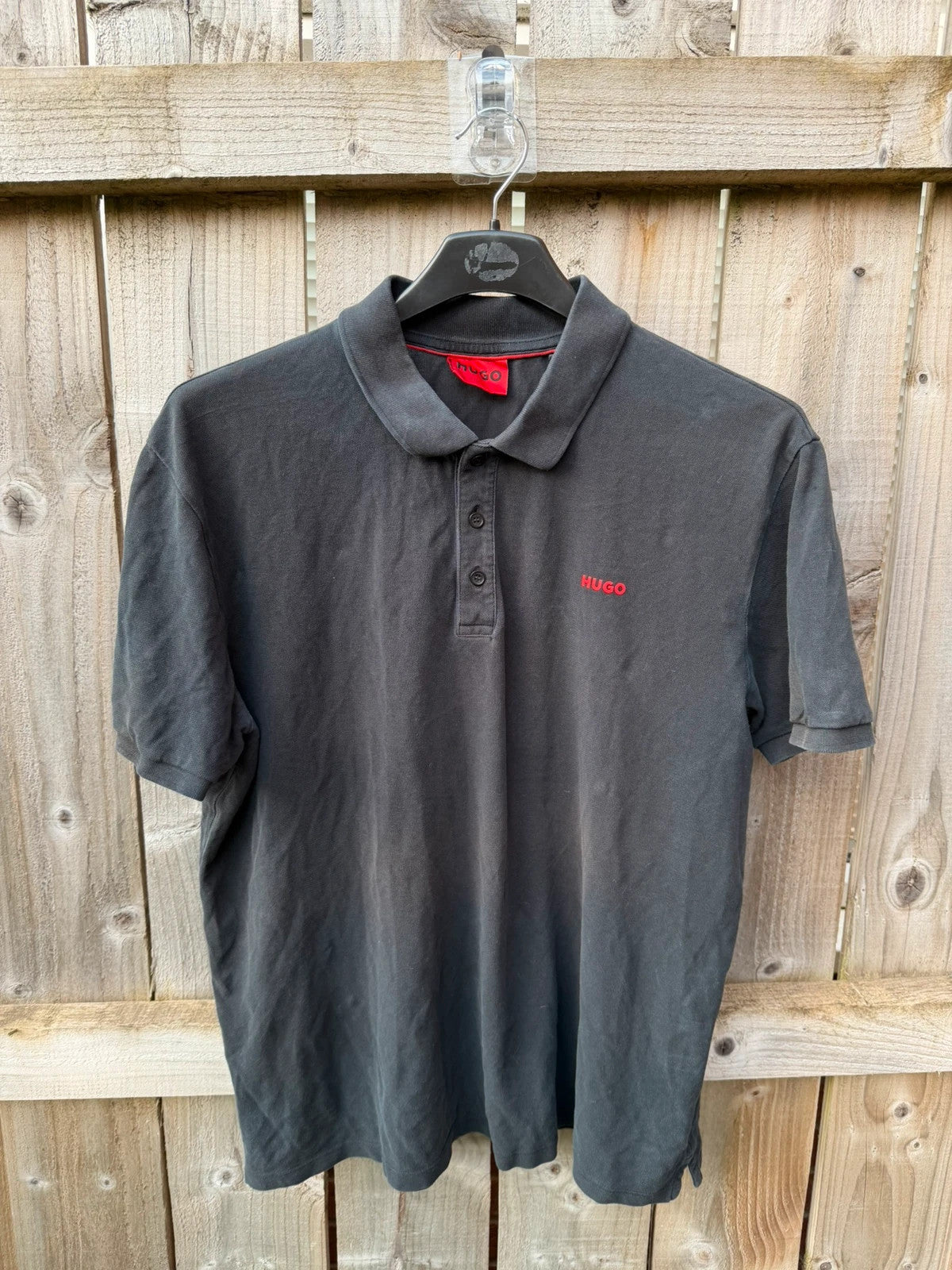 Hugo Boss black polo shirt with red logo, classic fit, premium cotton material.