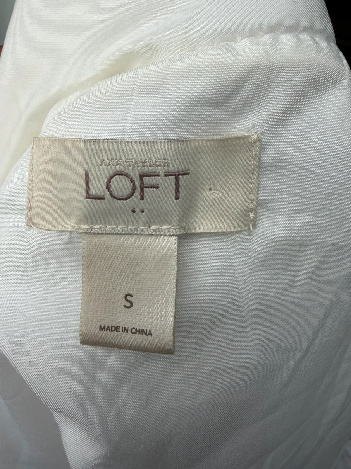 LOFT white sleeveless puffer vest with zip closure and lightweight material.