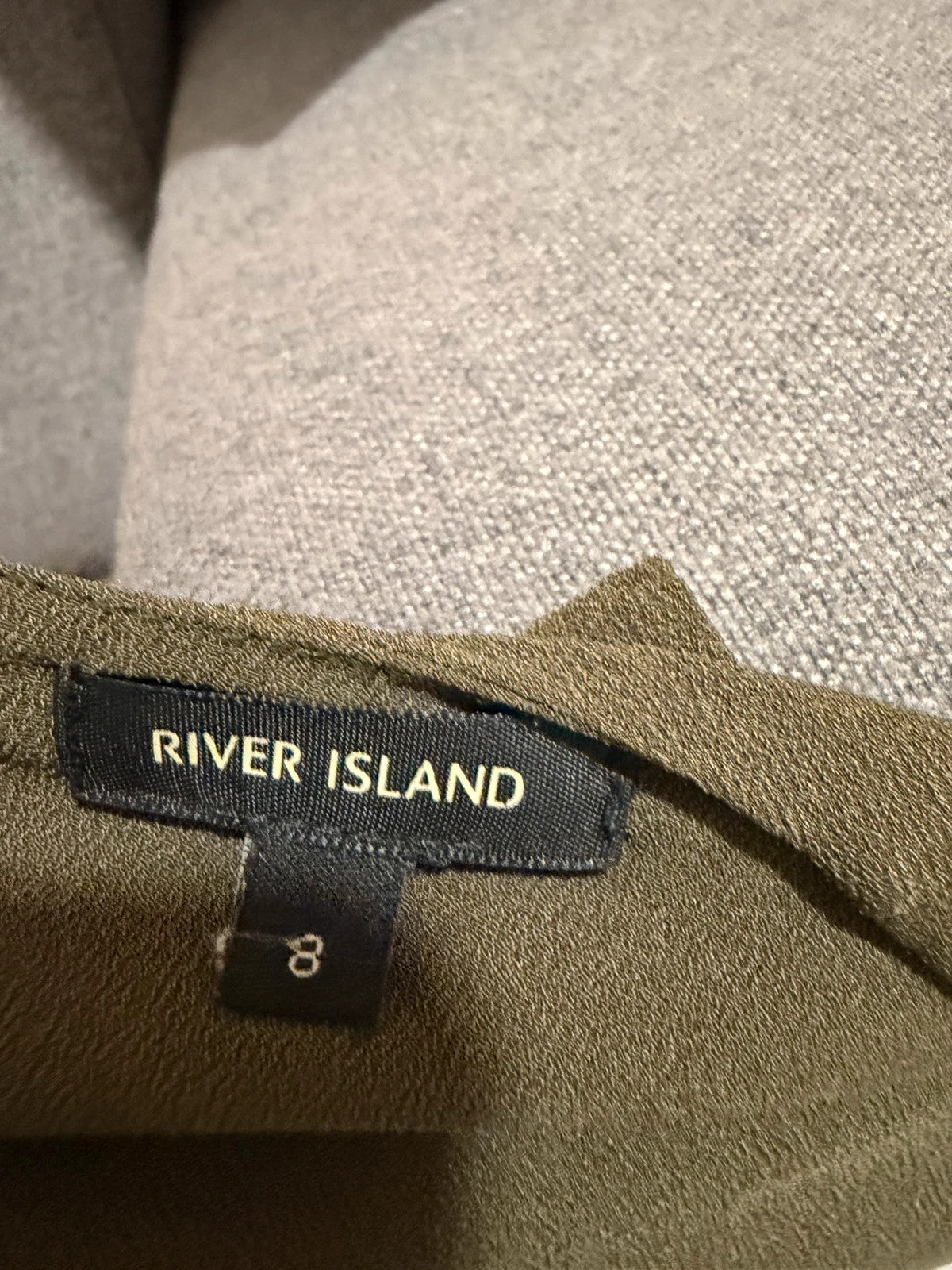 River Island khaki asymmetric sleeveless top with elegant design and smart silhouette.