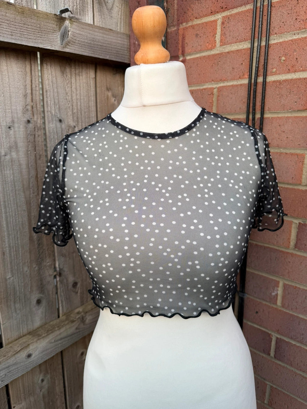 PrettyLittleThing black sheer mesh crop top with polka dot pattern and festival style.