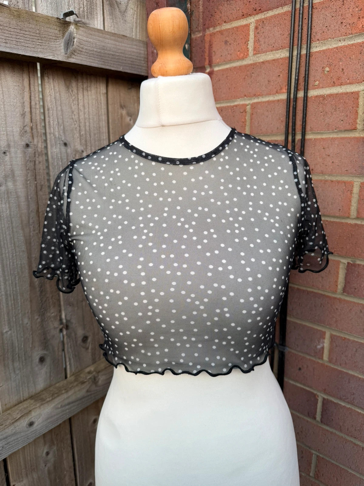 PrettyLittleThing black sheer mesh crop top with polka dot pattern and festival style.