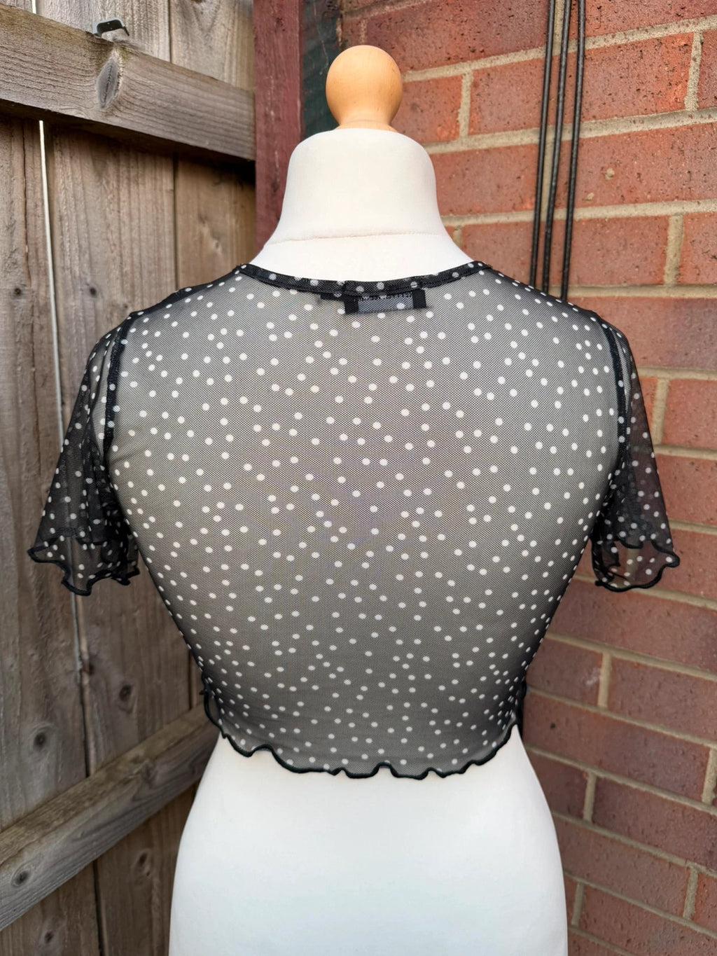 PrettyLittleThing black sheer mesh crop top with polka dot pattern and festival style.