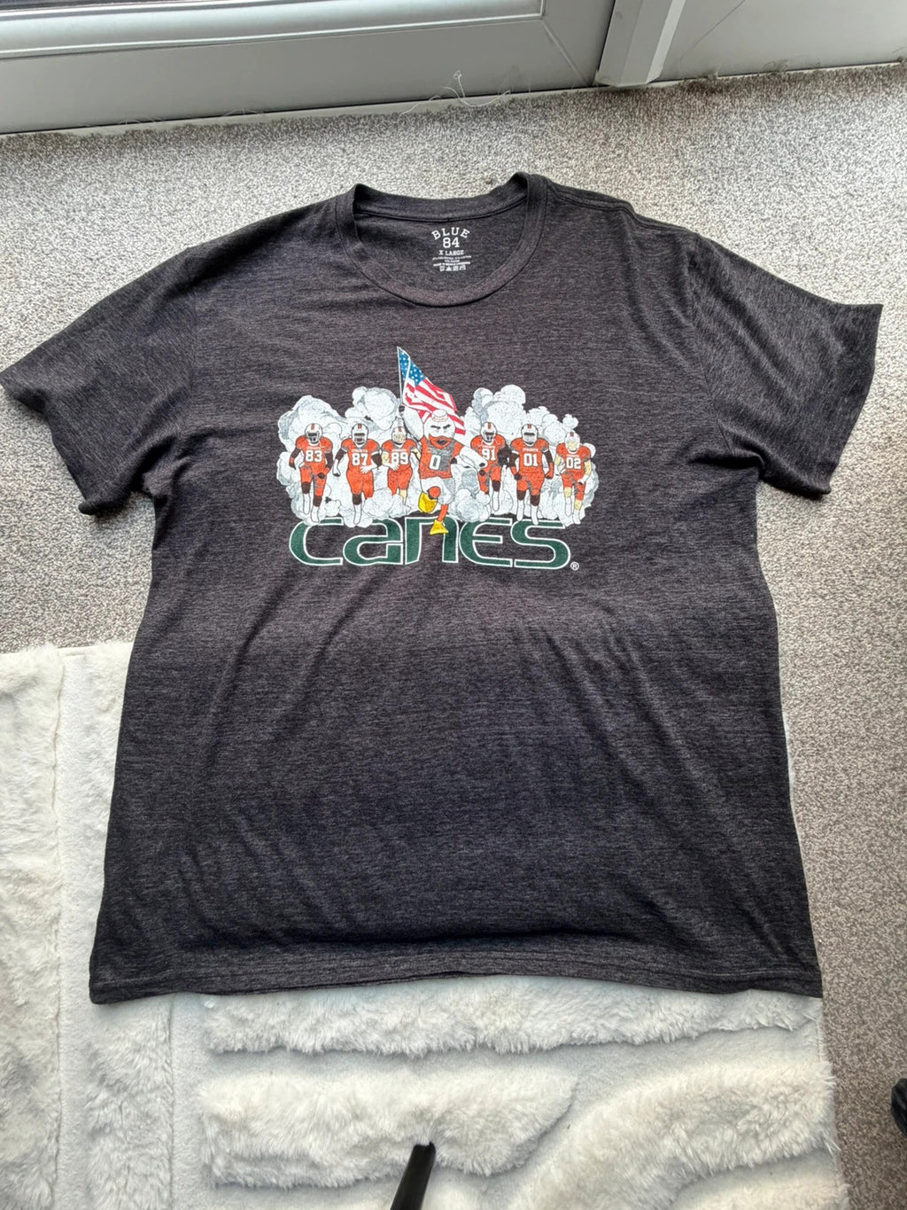 Blue 84 grey graphic tee featuring Miami Hurricanes logo and vintage design.