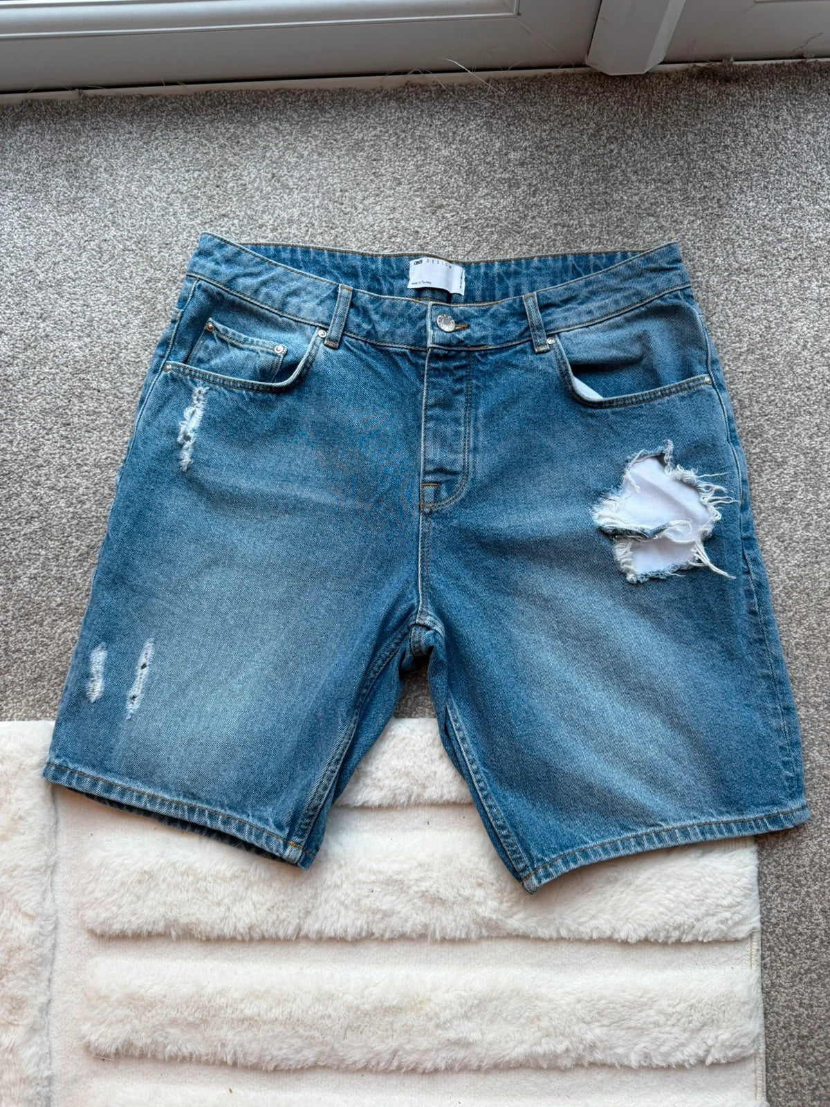 ASOS blue distressed denim shorts with frayed hem and casual Y2K style.