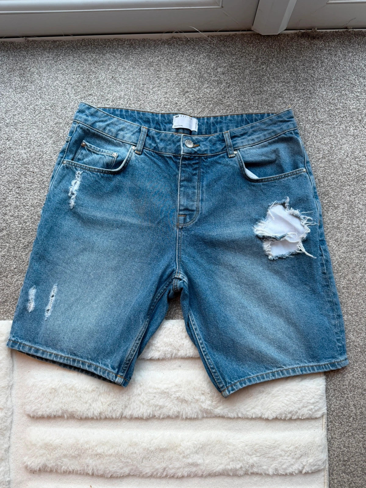 ASOS blue distressed denim shorts with frayed hem and casual Y2K style.