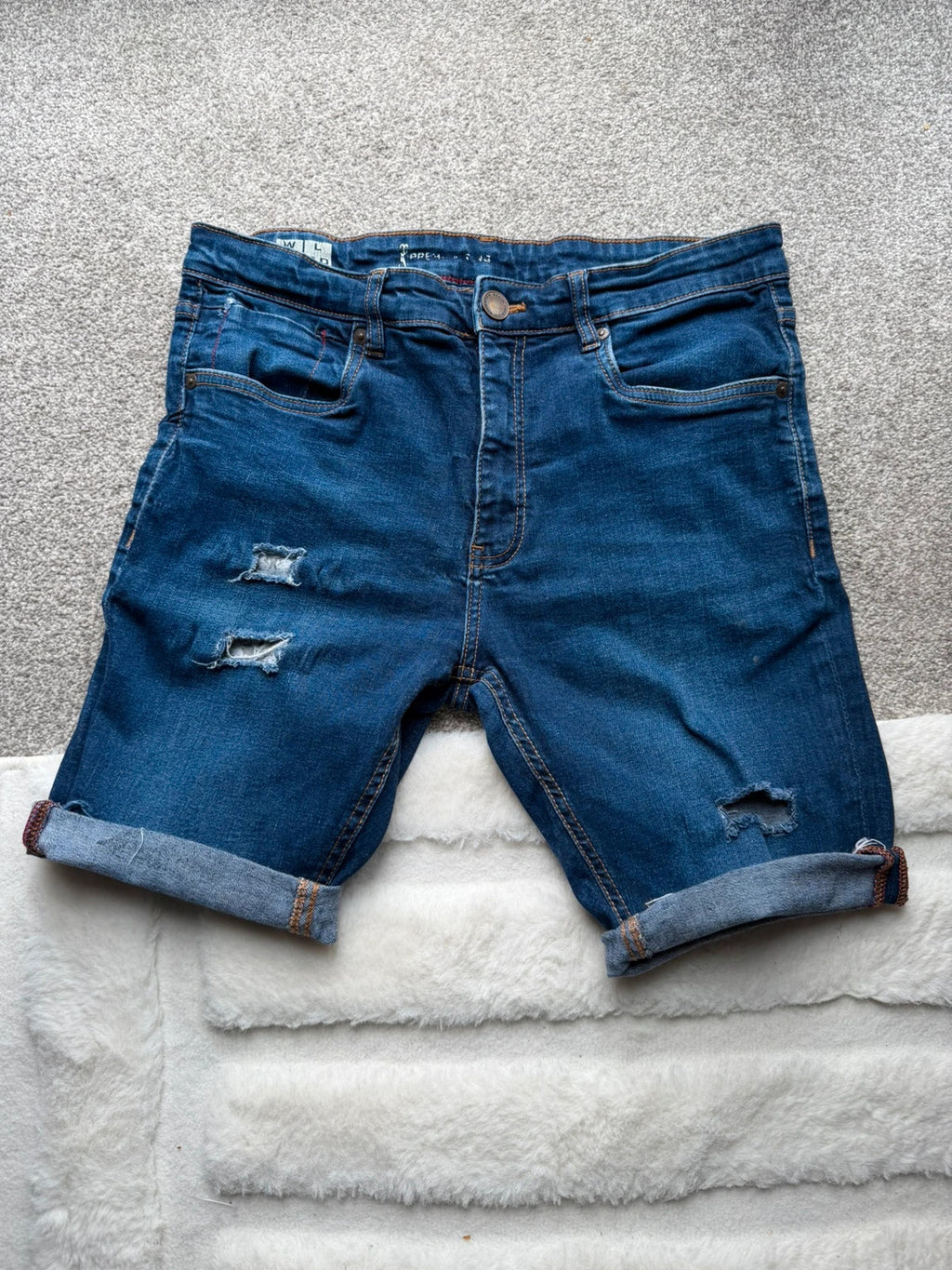 Ringspun blue denim shorts with distressed details and rolled hem.