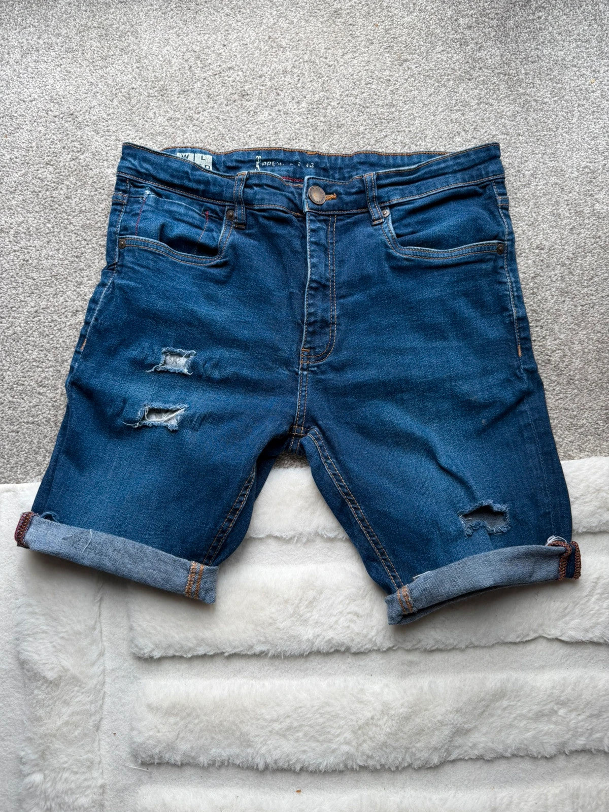 Ringspun blue denim shorts with distressed details and rolled hem.