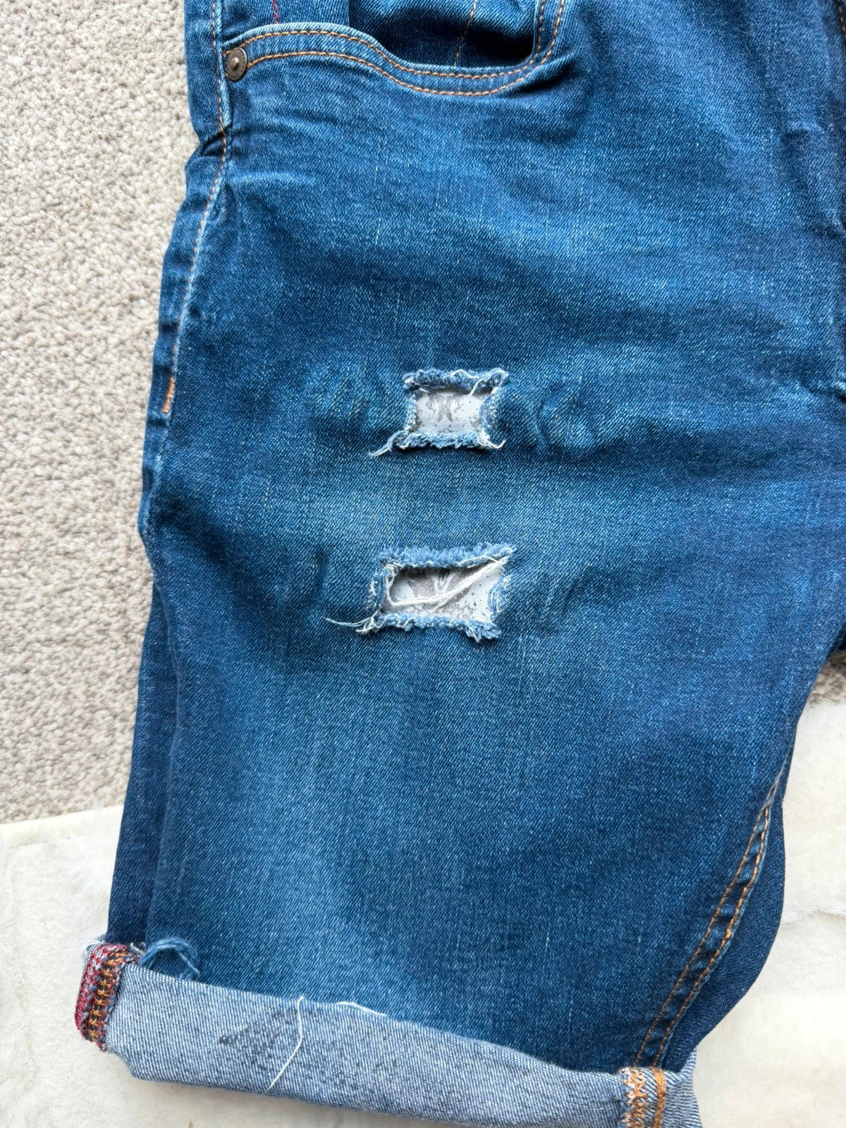 Ringspun blue denim shorts with distressed details and rolled hem.